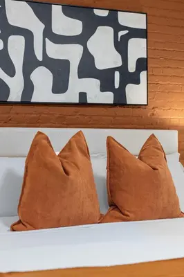 two brown pillows on a white shelf with a painting at Chic Modern Unit in NYC in Brooklyn