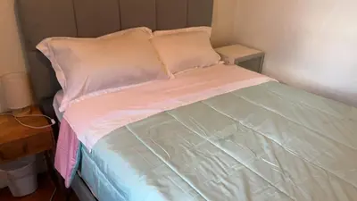 a unmade bed with pink and white sheets and pillows at 2218NColoradoC in Philadelphia