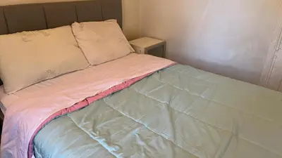 a unmade bed with a pink blanket and pillows at 2218NColoradoC in Philadelphia