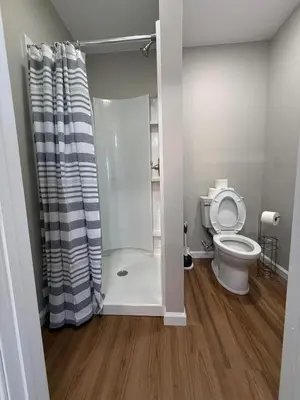 a bathroom with a shower and a toilet at Cozy Cottages Flexible Stays in Wrightsville