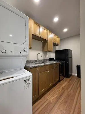 a kitchen with wooden cabinets and a white refrigerator at Cozy Cottages Flexible Stays in Wrightsville