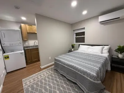 a small bedroom with a bed and a kitchen at Cozy Cottages Flexible Stays in Wrightsville