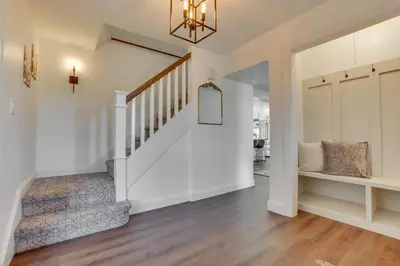 a hallway with white walls and a staircase with a mirror at Zook Manor with Hot tub Firepit and Game Room in Atglen