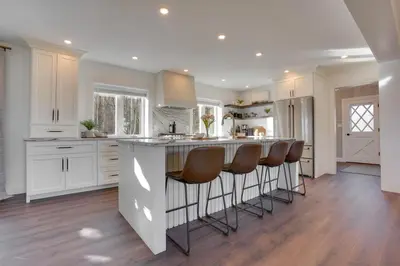 a kitchen with white cabinets and a island with bar stools at Zook Manor with Hot tub Firepit and Game Room in Atglen