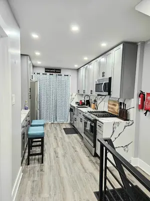 a large kitchen with white cabinets and a blue stool at Curacao vs Ivory Coast, Lock in NOW! Sleeps 14 in Philadelphia