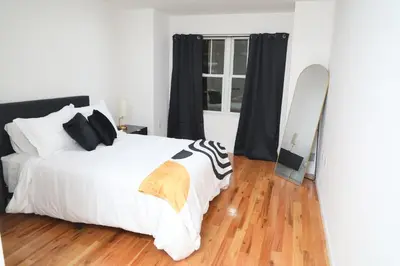 a bedroom with a large white bed and a mirror at Modern Minimalist Lux Paradise in Newark