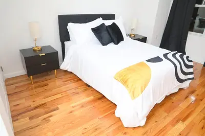 a bedroom with a large white bed and wooden floors at Modern Minimalist Lux Paradise in Newark