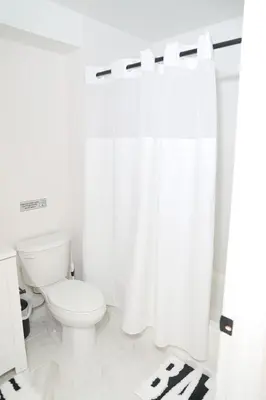 a bathroom with a toilet and a white shower curtain at Modern Minimalist Lux Paradise in Newark