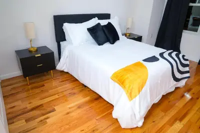 a bedroom with a large white bed and wooden floors at Modern Minimalist Lux Paradise in Newark