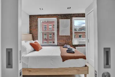 a bedroom with a bed and a brick wall at SoHo Designer 2BR with balcony in New York