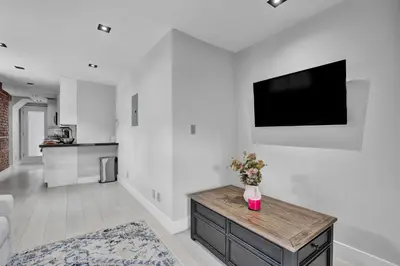 a living room with a tv on a white wall at SoHo Designer 2BR with balcony in New York