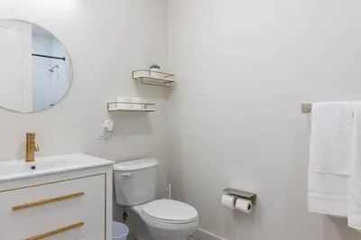 a white bathroom with a toilet and a mirror at Luxury Lookout with NYC view, 2BR plus Free Parking, Sleeps 8, 20 Percent Off in East Orange