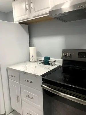 a kitchen with white cabinets and a black stove at A Cozy Corner with kitchen and parking in Drexel Hill