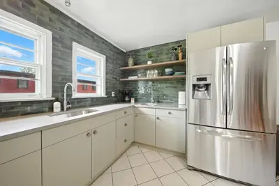 a kitchen with white cabinets and a stainless steel refrigerator at Liberty Lakefront Home - Pool, Hot Tub, Sauna in Liberty
