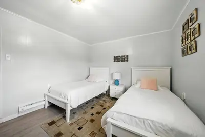 two beds in a bedroom with white walls and wooden floors at Liberty Lakefront Home - Pool, Hot Tub, Sauna in Liberty