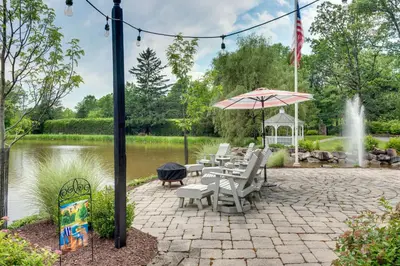 a patio with chairs and an umbrella and a fountain at Fish and Hike Lakeside Poconos Retreat, Unit 3 in Bangor