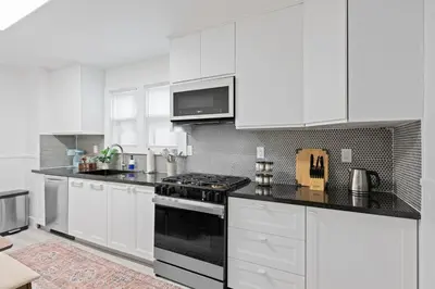 a white kitchen with a stove and white cabinets at 15m to NY Cozy Relaxing Home in Hackensack