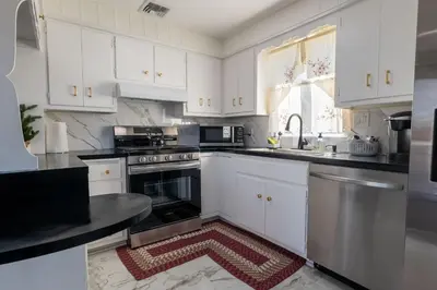 a kitchen with white cabinets and a rug on the floor at New 3 Bed & 1 Bed Apt Lake Park Station EWR Airport Path Train Subway Bus Hospital Rahway NJ Manhattan NYC in Rahway