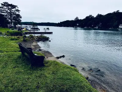 a park bench sitting next to a body of water at Italy Inspired Lakeview Chalet with Hot Tub in Lake Harmony