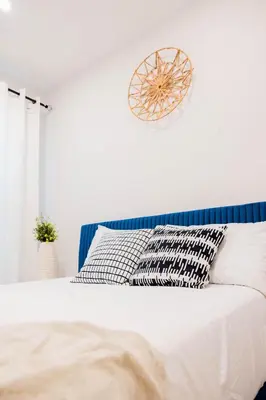 a white bedroom with a bed with a blue headboard at Joynest Place in Newark