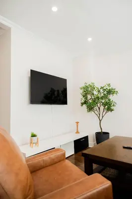 a living room with a couch and a tv on a wall at Joynest Place in Newark