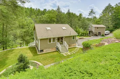 a small green house on a grassy hill at 13 Mi to Ski Big Bear Updated Getaway with Deck in Shohola