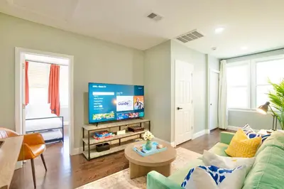 a living room with a green couch and a flat screen tv at The Hillside | Full House | Parking | Near EWR-NYC in Newark