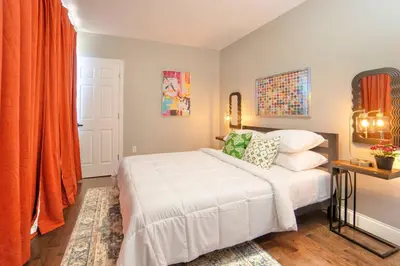a bedroom with a white bed and orange curtains at The Hillside | Full House | Parking | Near EWR-NYC in Newark