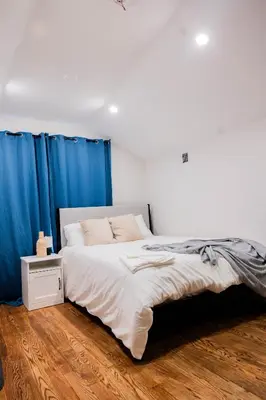 a bedroom with a large bed with blue curtains at Joynest Loft - Private Entry & Bath in Newark