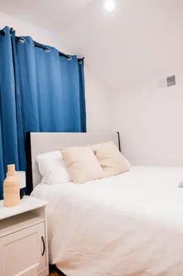 a bedroom with two beds with blue curtains at Joynest Loft - Private Entry & Bath in Newark
