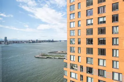 a tall orange building next to a body of water at Blueground Battery Park City rooftop nr Hudson River NYC-586 in New York