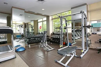 a gym with several tread machines and a mirror at Blueground Battery Park City rooftop nr Hudson River NYC-586 in New York