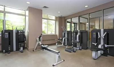 a gym with treadmills and ellipticals in a room with windows at Blueground Battery Park City rooftop nr Hudson River NYC-586 in New York