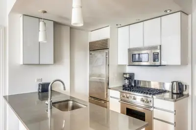 a kitchen with white cabinets and stainless steel appliances at Blueground Hells Kitchen view nr Hudson River NYC-1905 in New York