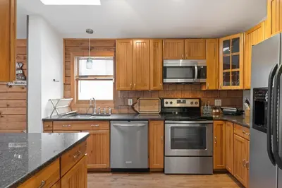 a kitchen with wooden cabinets and stainless steel appliances at 5 min to Lake Chic Cozy Hot Tub in Sparta