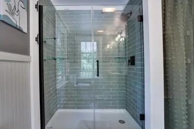 a bathroom with a tub and a shower with blue tiles at Heatherbell, A Lakeside Retreat in Saylorsburg