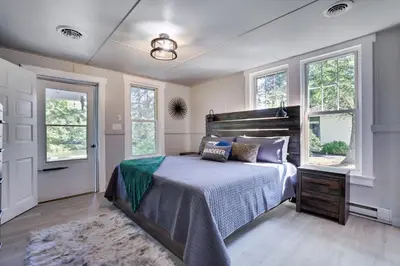 a bedroom with a bed and two windows at Heatherbell, A Lakeside Retreat in Saylorsburg
