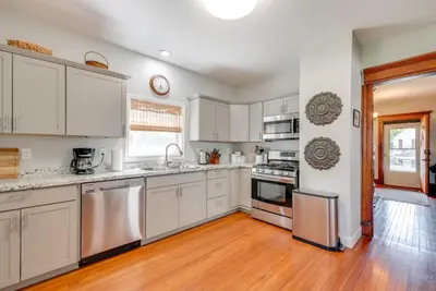 a kitchen with white cabinets and a wooden floor at 6 Mi to Montage Mtn Resort! Family Home with Yard in Scranton