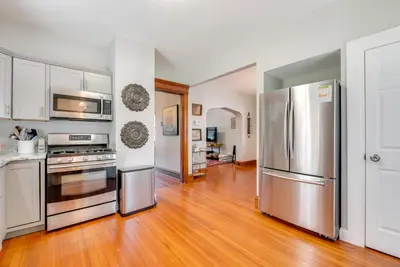 a kitchen with stainless steel appliances and wooden floors at 6 Mi to Montage Mtn Resort! Family Home with Yard in Scranton