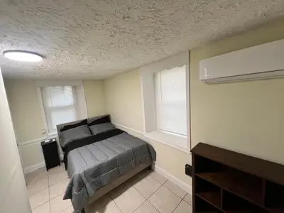 a bedroom with a bed and two windows at Your Comfortable Home Away From Home in North Bergen