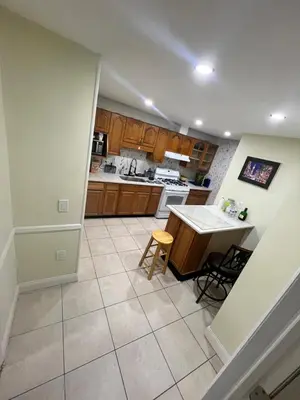a kitchen with wooden cabinets and a tile floor at Your Comfortable Home Away From Home in North Bergen
