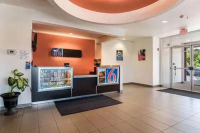 a lobby with a tv and paintings on the wall at Motel 6 Wilkes Barre Arena in Wilkes-Barre