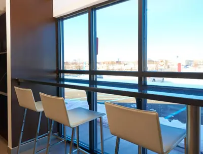 a bar with white chairs and a large window at Motel 6 Wilkes Barre Arena in Wilkes-Barre