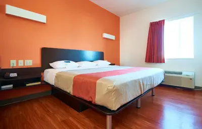 a bedroom with a large bed with an orange wall at Motel 6 Wilkes Barre Arena in Wilkes-Barre