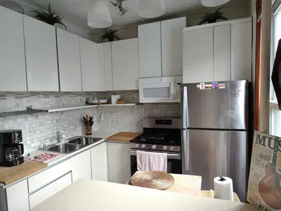 a kitchen with white cabinets and a stainless steel refrigerator at Cozy apartment in Brooklyn