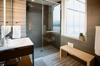 a bathroom with a shower and a sink and a window at Modern Designer Stunning Hudson Views Corner Unit in New York