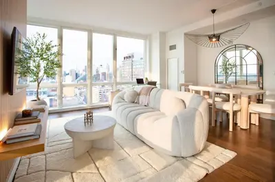 a living room with a white couch and a table at Modern Designer Stunning Hudson Views Corner Unit in New York