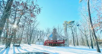 a house in the woods with snow on the ground at Cozy 4-Season Chalet w Arcades & Lake, Ski Lifts in Lackawaxen