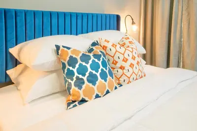 a bed with a blue headboard and pillows on it at Sky Walk at The Hillside in Newark