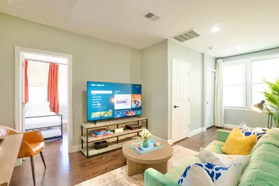 a living room with a green couch and a flat screen tv at Sky Walk at The Hillside in Newark